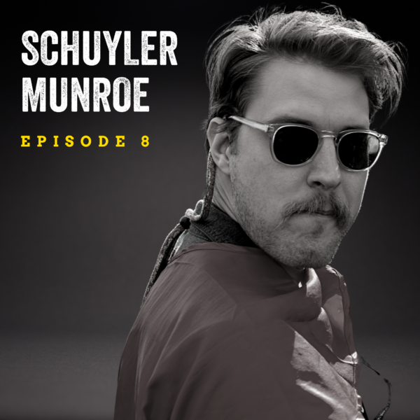 Black and white image of a man wearing sunglasses and a mustache turns toward the camera. The background is dark and a text overlay reads "Schuyler Munroe Episode 8."