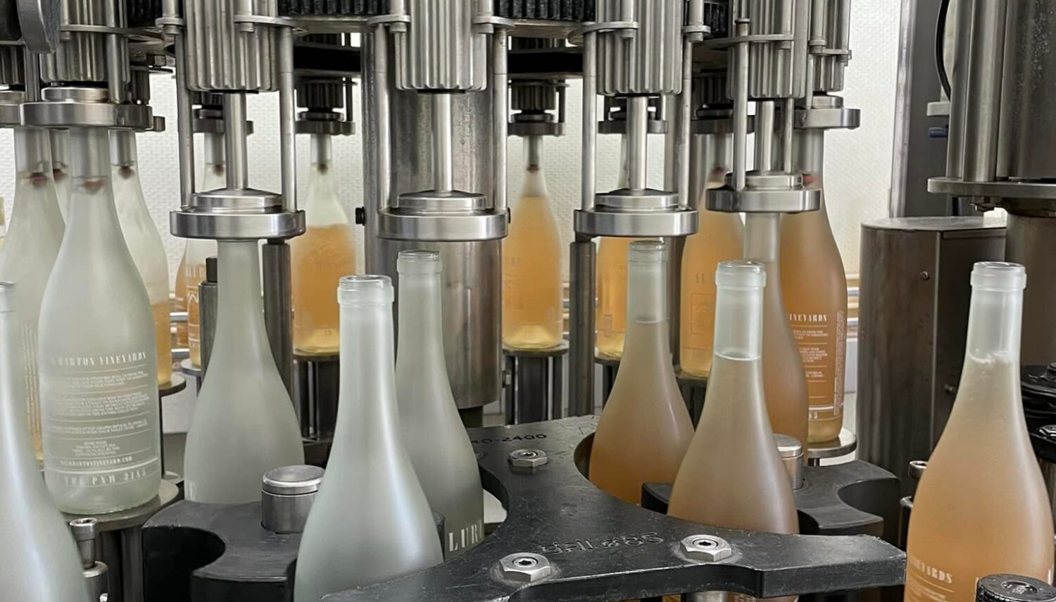 a machine holds frosted bottles, some filled with rose wine and others empty