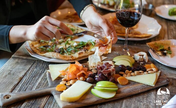 People enjoying a beautiful charcuterie board, pizza and wine in Lake Chelan Wine Valley. 